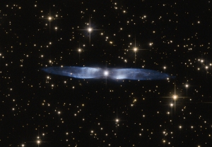 In this cosmic snapshot, the spectacularly symmetrical wings of Hen 2-437 show up in a magnificent icy blue hue. Hen 2-437 is a planetary nebula, one of around 3000 such objects known to reside within the Milky Way. Located within the faint northern constellation of Vulpecula (The Fox), Hen 2-437 was first identified in 1946 by Rudolph Minkowski, who later also discovered the famous and equally beautiful M2-9 (otherwise known as the Twin Jet Nebula). Hen 2-437 was added to a catalogue of planetary nebula over two decades later by astronomer and NASA astronaut Karl Gordon Henize. Planetary nebulae such as Hen 2-437 form when an aging low-mass star — such as the Sun — reaches the final stages of life. The star swells to become a red giant, before casting off its gaseous outer layers into space. The star itself then slowly shrinks to form a white dwarf, while the expelled gas is slowly compressed and pushed outwards by stellar winds. As shown by its remarkably beautiful appearance, Hen 2-437 is a bipolar nebula — the material ejected by the dying star has streamed out into space to create the two icy blue lobes pictured here.