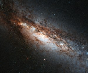This new Hubble image shows a peculiar galaxy known as NGC 660, located around 45 million light-years away from us. NGC 660 is classified as a "polar ring galaxy", meaning that it has a belt of gas and stars around its centre that it ripped from a near neighbour during a clash about one billion years ago. The first polar ring galaxy was observed in 1978 and only around a dozen more have been discovered since then, making them something of a cosmic rarity. Unfortunately, NGC 660’s polar ring cannot be seen in this image, but has plenty of other features that make it of interest to astronomers – its central bulge is strangely off-kilter and, perhaps more intriguingly, it is thought to harbour exceptionally large amounts of dark matter. In addition, in late 2012 astronomers observed a massive outburst emanating from NGC 660 that was around ten times as bright as a supernova explosion. This burst was thought to be caused by a massive jet shooting out of the supermassive black hole at the centre of the galaxy.